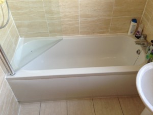 Bath fitted to cream tile with shower door over bath