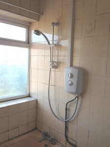 Old bathroom shower with pipes and cables in display