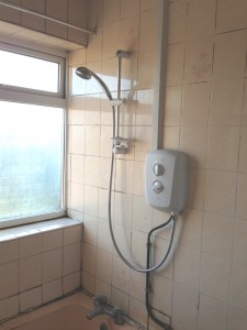 Old bathroom shower with pipes and cables in display