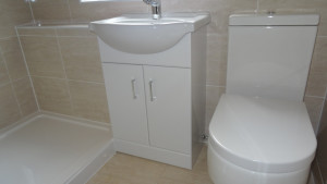 Vanity Basin and Toilet fitted against a beige Travertine wall tile