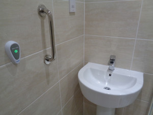 Bathroom sink on tiled wall. Grab rail for disabled person