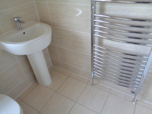 Chrome Towel Warmer with Pedestal Basin and Beige Bathroom TIles