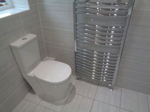 Modern Toilet with Grey Travertine Tiles and Chrome Towel Warmer