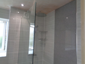 Thermostatic shower with grey wall tiles and grey feature wall panel