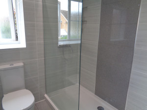 Modern walk in shower room with grey tiles and feature wall