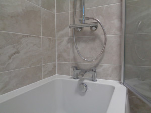 Chrome bath taps fitted below the wall mounted thermostatic shower