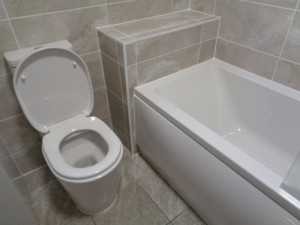 Boxed and tiled in empty space at the end of a bath