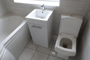 Modern Bathroom suite including P shaped Shower bath, vanity basin and toilet with grey bathroom tiles