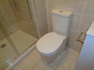 Toilet fitted to ensuite wall with beige British ceramic tiles