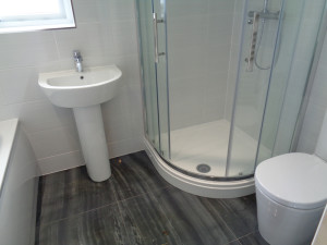 Bathroom Sink Shower and Toilet with white wall tiles and black floor tiles