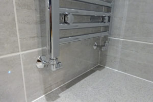 Bathroom towel warmer chrome pipes coming from wall