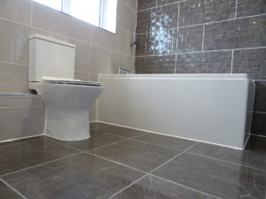 Bathroom walls and floor tiled with grey tiles and feature tiles
