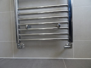 Bathroom fitted with chrome towel warmer fully tiled
